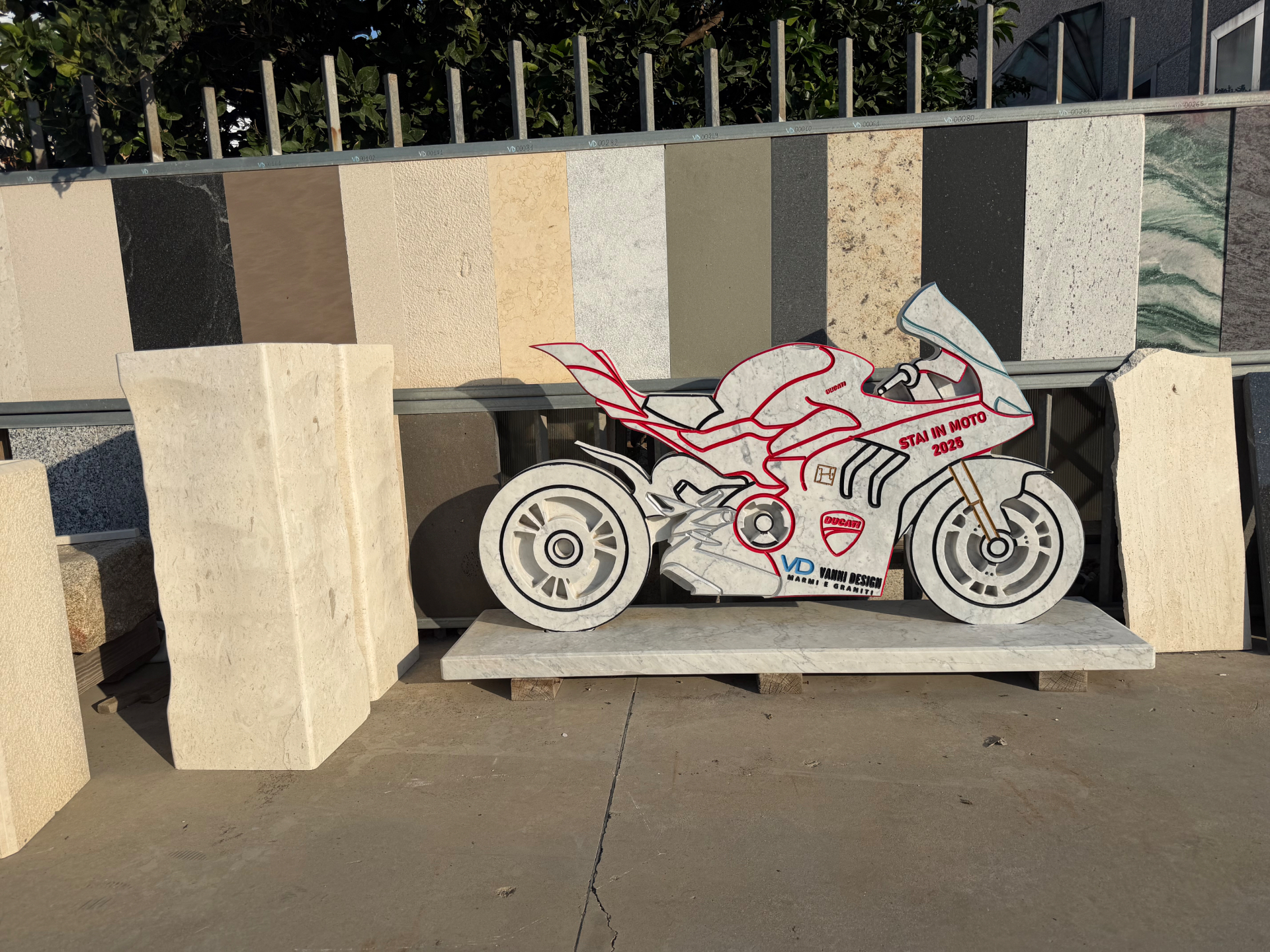 Scultura a forma di moto in marmo bianco con intarsi colorati, realizzata da Vanni Design